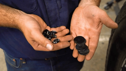 Braden holds both hands at waist height in front of him. One hand holds bolts and nuts and the other holds washers.