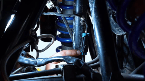 You can see a hand reach up into the dark inner parts of the UTV and unclip an electrical plug.