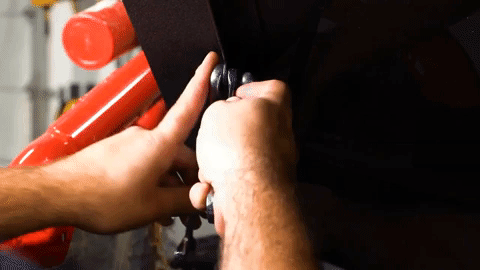 A man uses two wrenches to tighten the bolts on the struts where they connect to the lid of the bed enclosure.