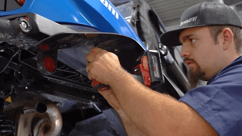 We see a bolt fall out of the back of the fender flare as Braden drills into it further up.
