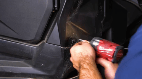 Braden uses a red Milwaukee drill to remove a bolt from the OEM fender.