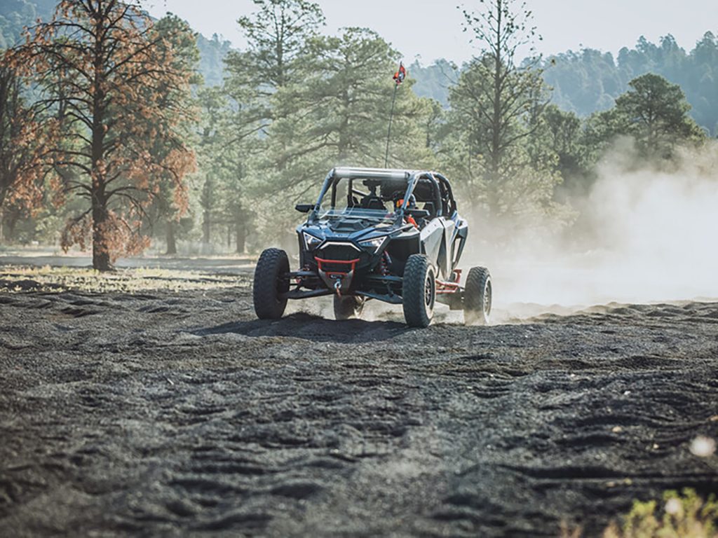 A Polaris RZR Pro R speeds down a bumpy gravel trail.