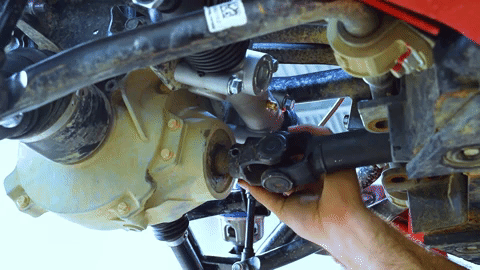 Braden gently taps the pin into the drive shaft and differential with a hammer.