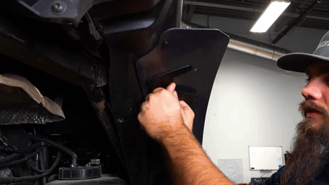 Braden aligns a metal bracket with the underside of the rear fender flare.