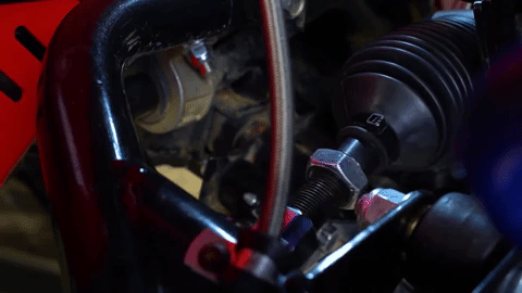 A shiny billet aluminum hexagonal tie rod is slowly wound onto the tie rod end.