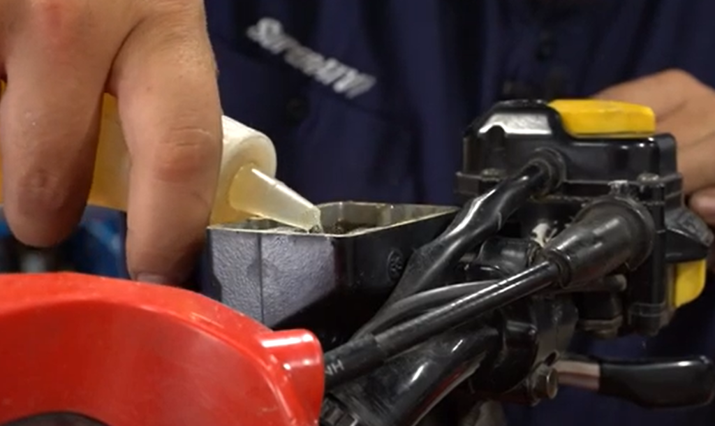 A person pouring more brake fluid into an ATV's master cylinder.