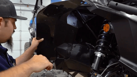 Braden crouches down and marks the holes for drilling on the OEM fender with a paint marker.