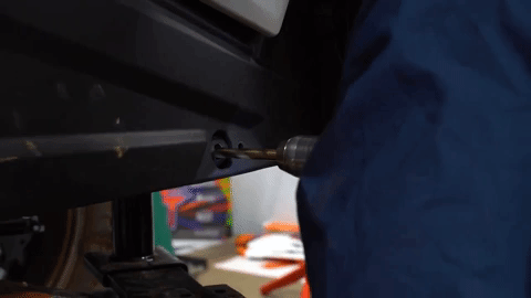 A drill makes a small hole in the frame of the UTV.