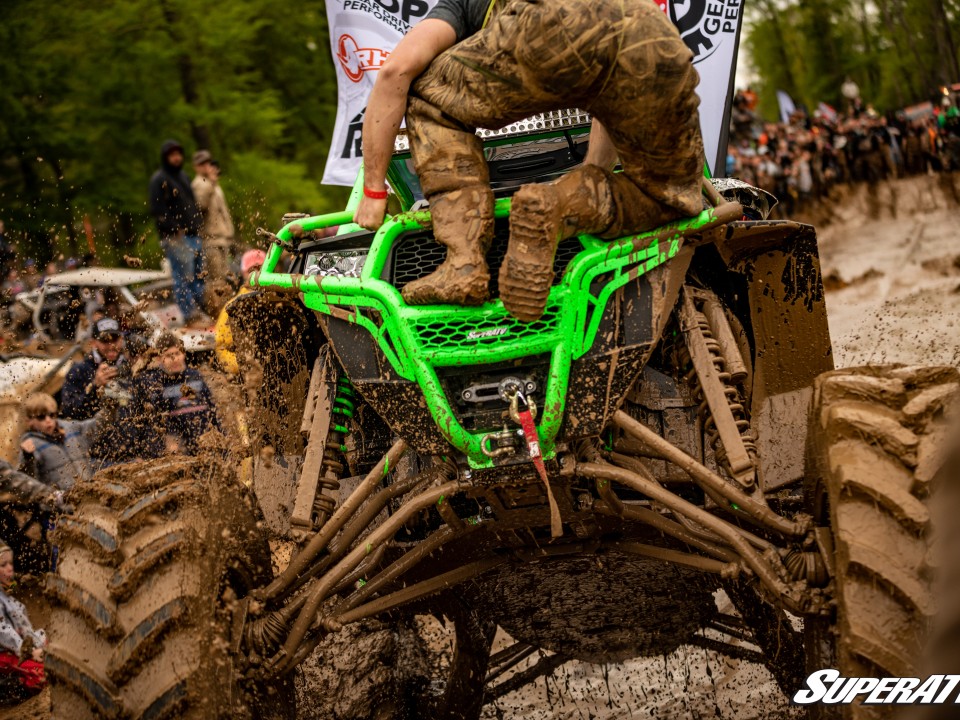 man sitting on front of Polaris RZR while mudding