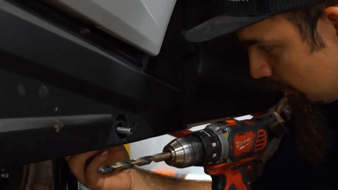 Braden slides a bolt through the back of the hole we just saw drilled in the last image. He's still holding the drill in one hand.
