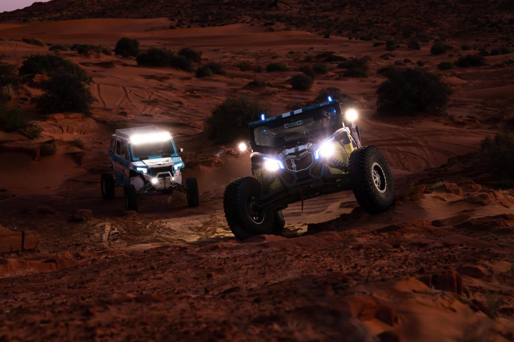 Two side-by-sides taking on desert rocks in the dark.