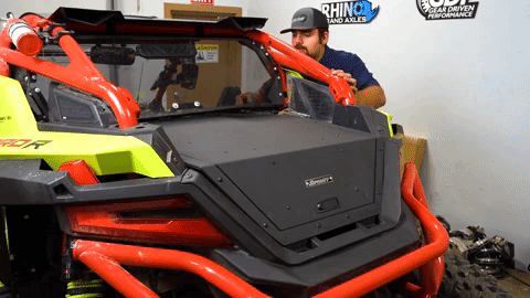 Braden reaches around the back of the machine to wiggle the bed enclosure as he adjust it along the rear windshield.