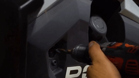 The drill makes a hole through a different part of the UTV's frame near the fuel tank.