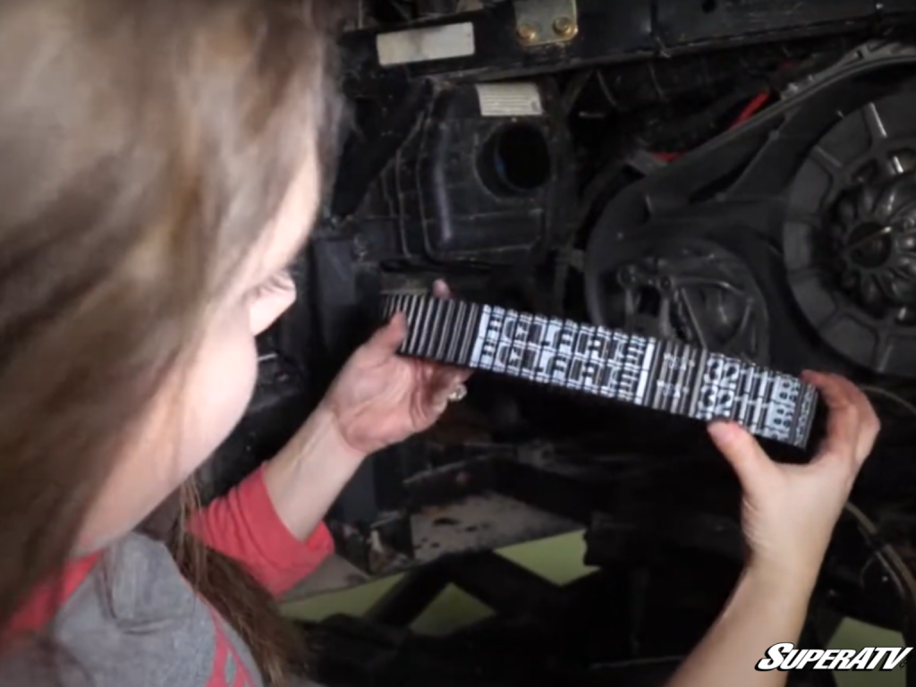 A woman examines the text on a Polaris drive belt.