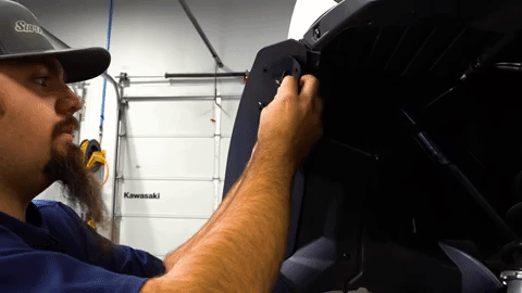 Braden aligns a U-shaped metal bracket with the OEM fender and the fender flare.