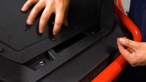 A pair of hands lifts the bed enclosure and slides a spacer underneath.