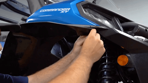 Braden inserts another push pin into the fender flare at the very front of the machine almost directly under the head light.