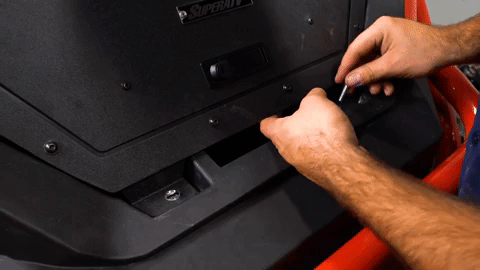 Two hands twist a bolt into the right side of the bed enclosure.