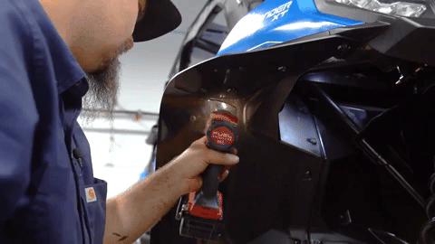 Braden squeezes under the fender of the Can-Am Commander to drill a hole through the fender flare.