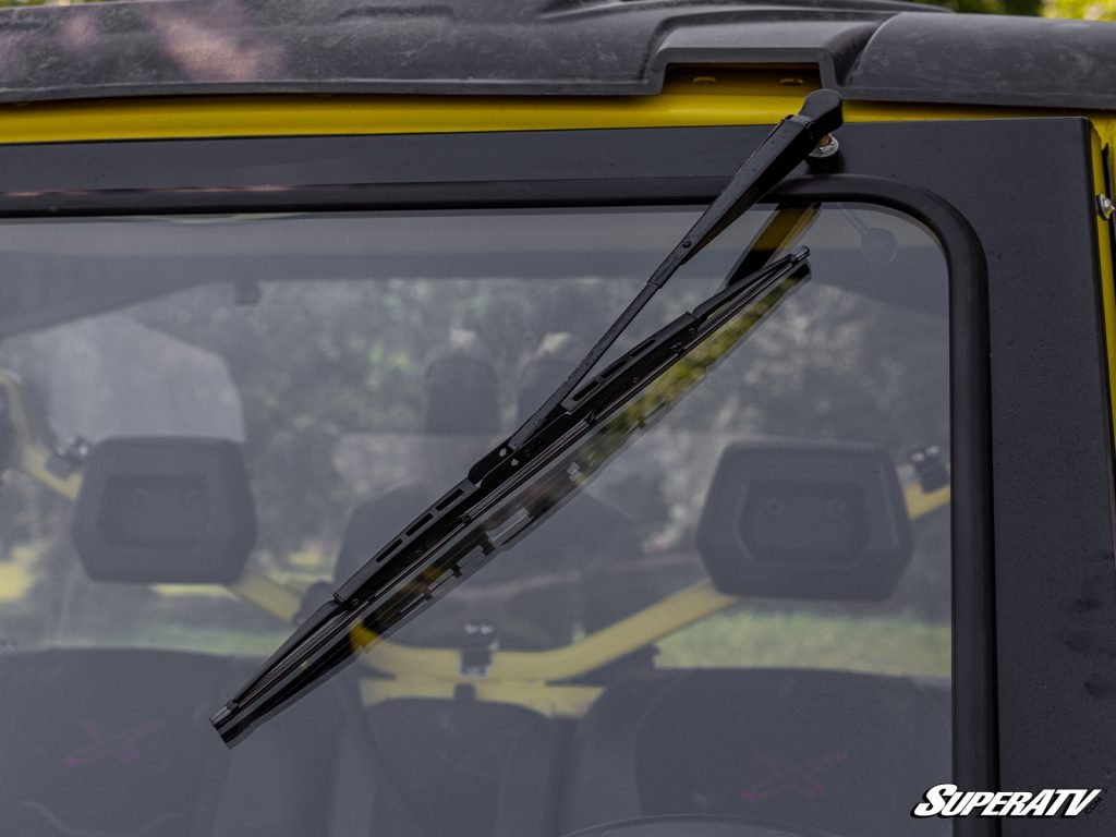 A glass windshield with a manual wiper installed on a side-by-side