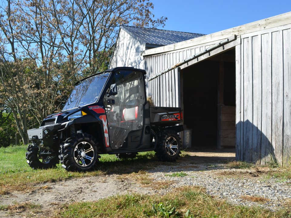 A Polaris Ranger parked in front of an open shed door.