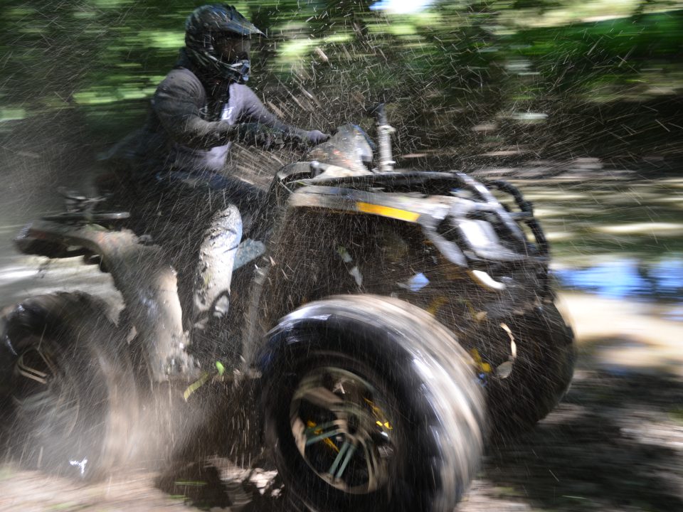 An ATV throwing mud and dirt as it speeds past.