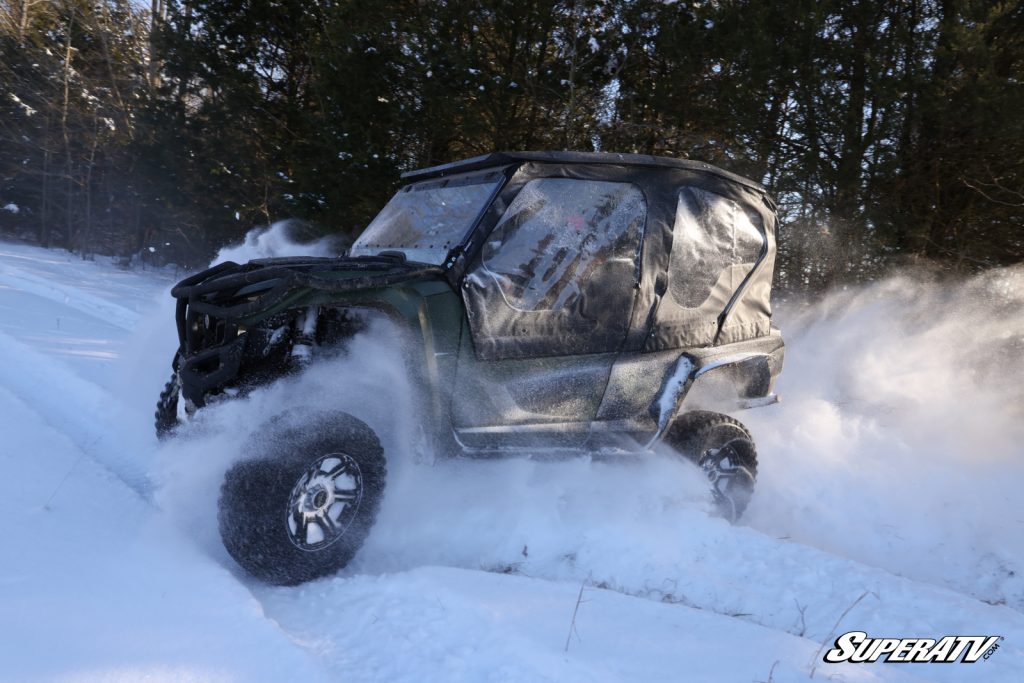 A soft cab enclosure on a UTV driving in the snow.