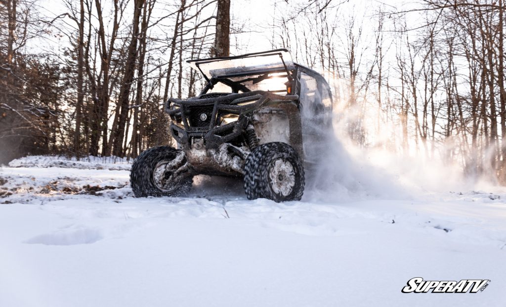 A Yamaha Wolverine RMAX riding through the snow with a full cab enclosure.