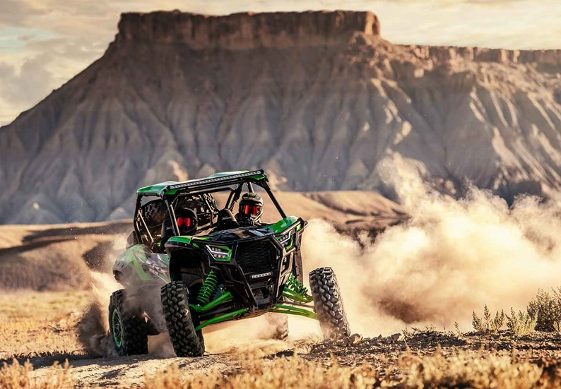 Kawasaki Teryx KRX drifting through sand in front of rock mountain