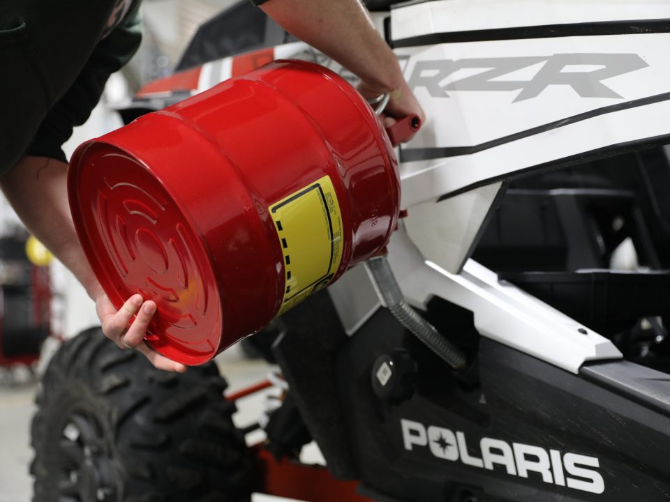 A person pouring gas into a Polaris RZR