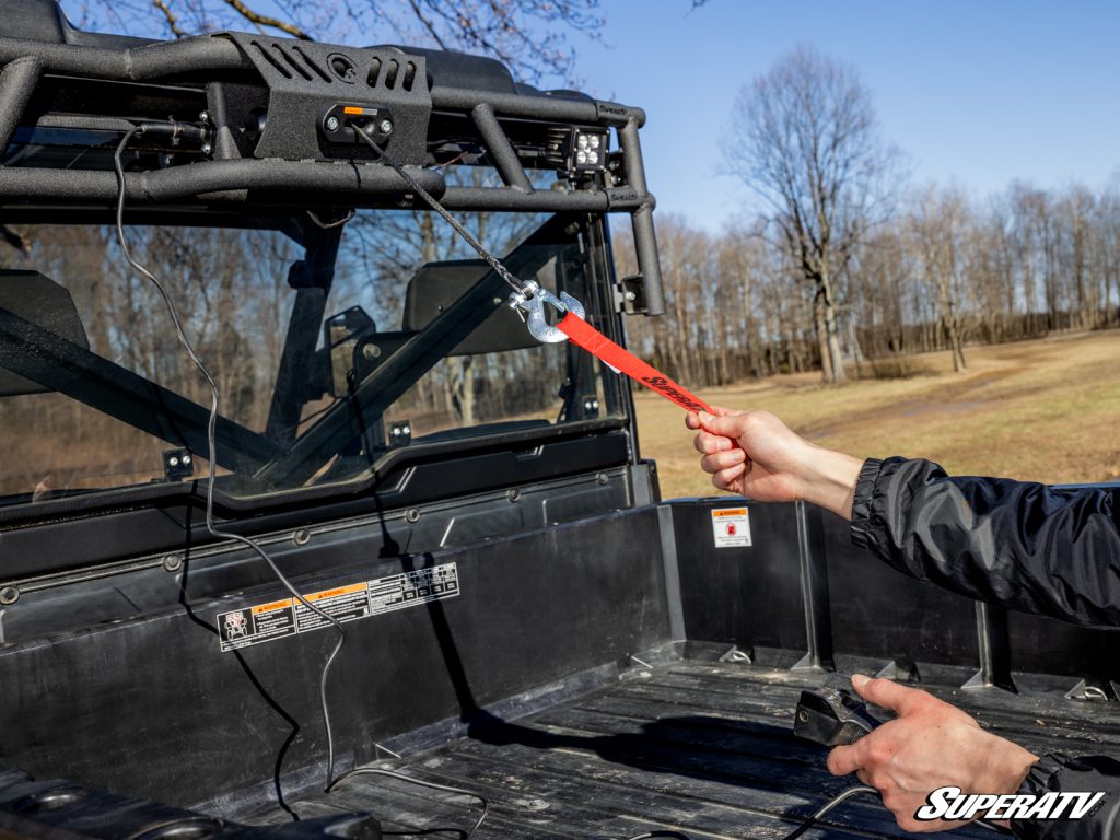 A person holding the strap on a Polaris Ranger bed winch.