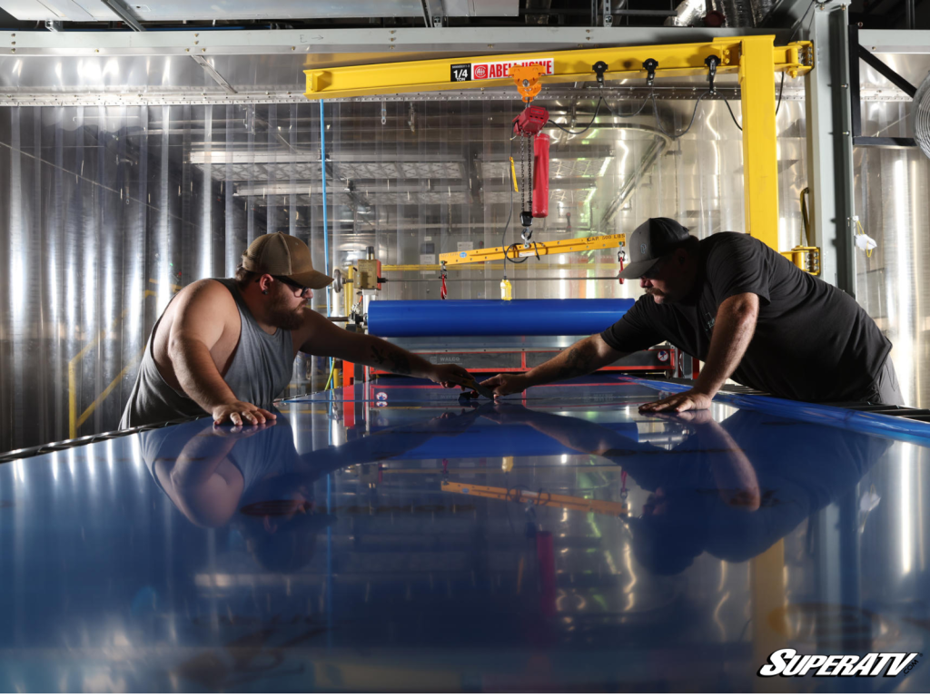 Two men working with a large piece of polycarbonate in a factory setting
