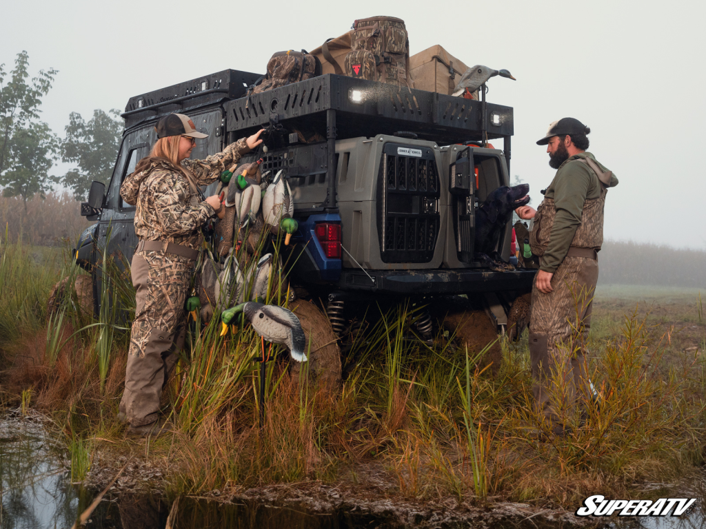 Two people unload an Outfitter Bed Rack to prepare for a duck hunt.
