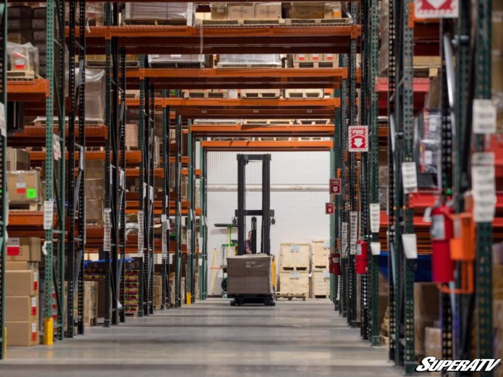 A forklift operator moves through a SuperATV warehouse.