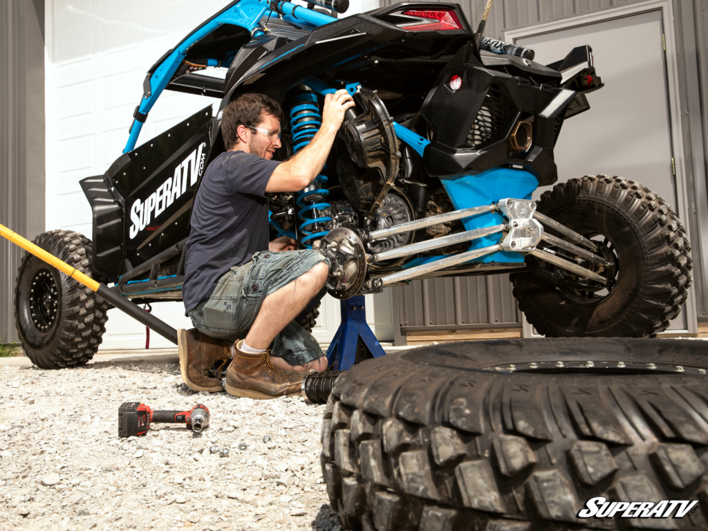 A mechanic pulling the clutch cover off a UTV.