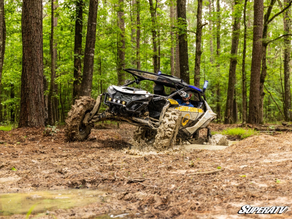 A modified Can-Am Maverick R tearing up a deep mud hole.