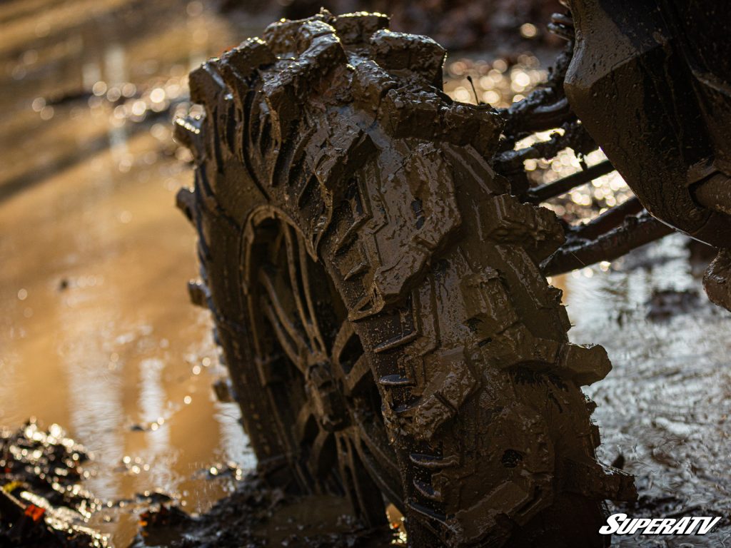 A giant tire with huge lugs digging through the mud.