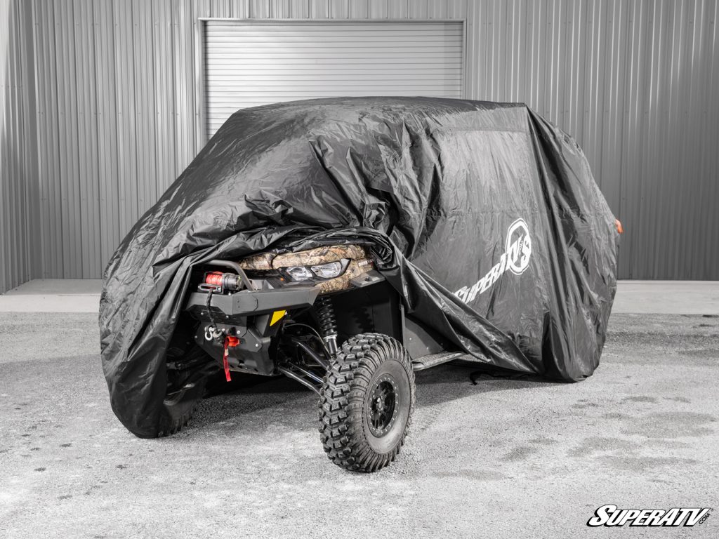 A Can-Am Defender peeks out from under a black UTV cover.