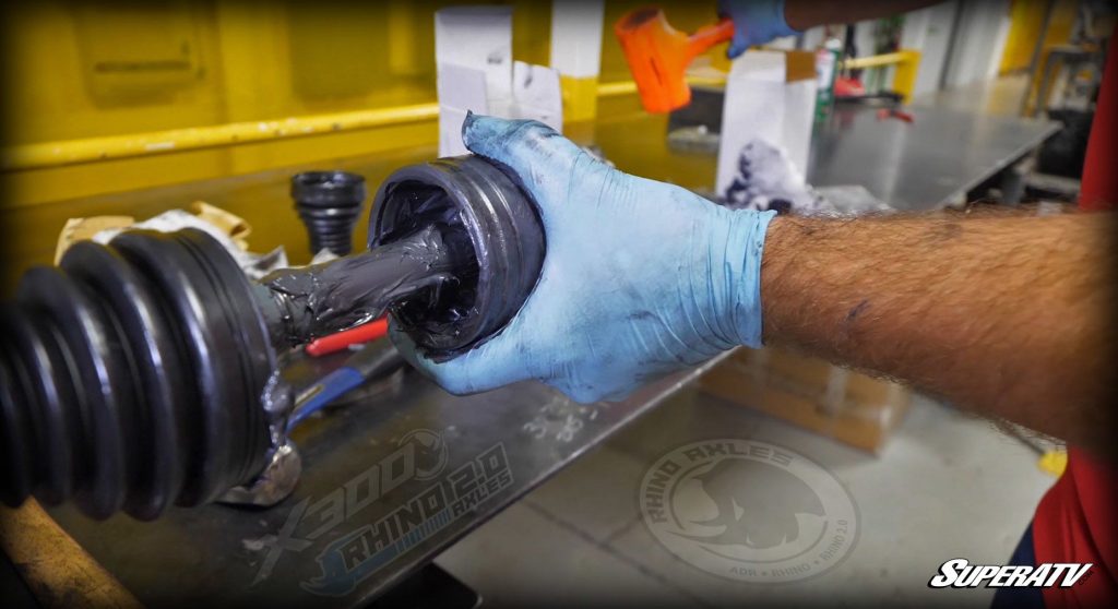 A UTV or ATV axle on a workbench with its boot removed, revealing grease.