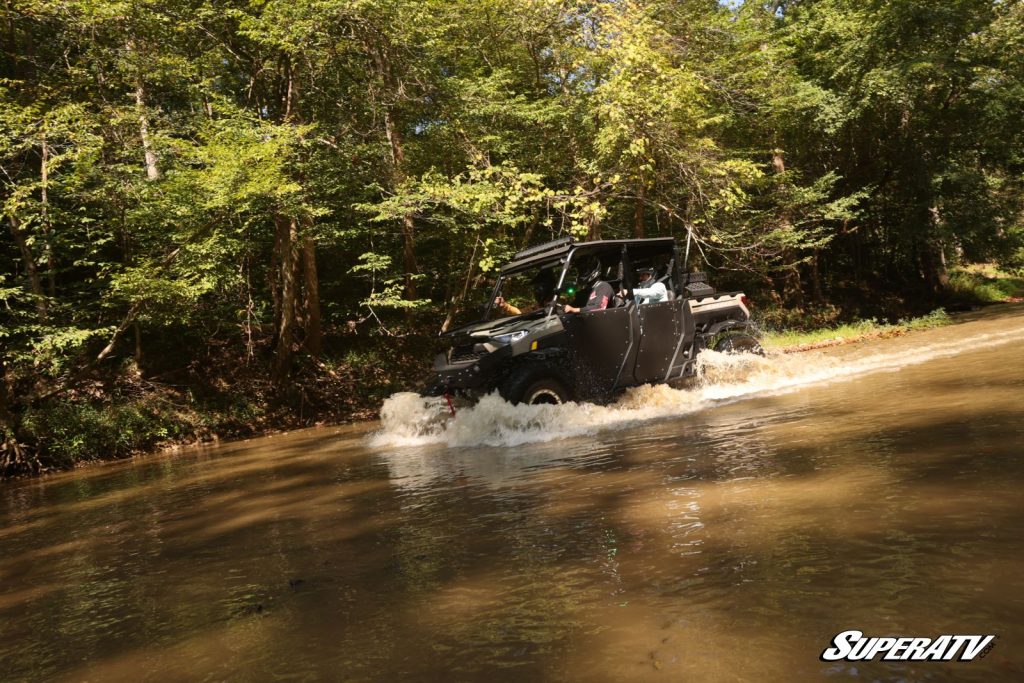 A Polaris Ranger Crew riding in a creek.