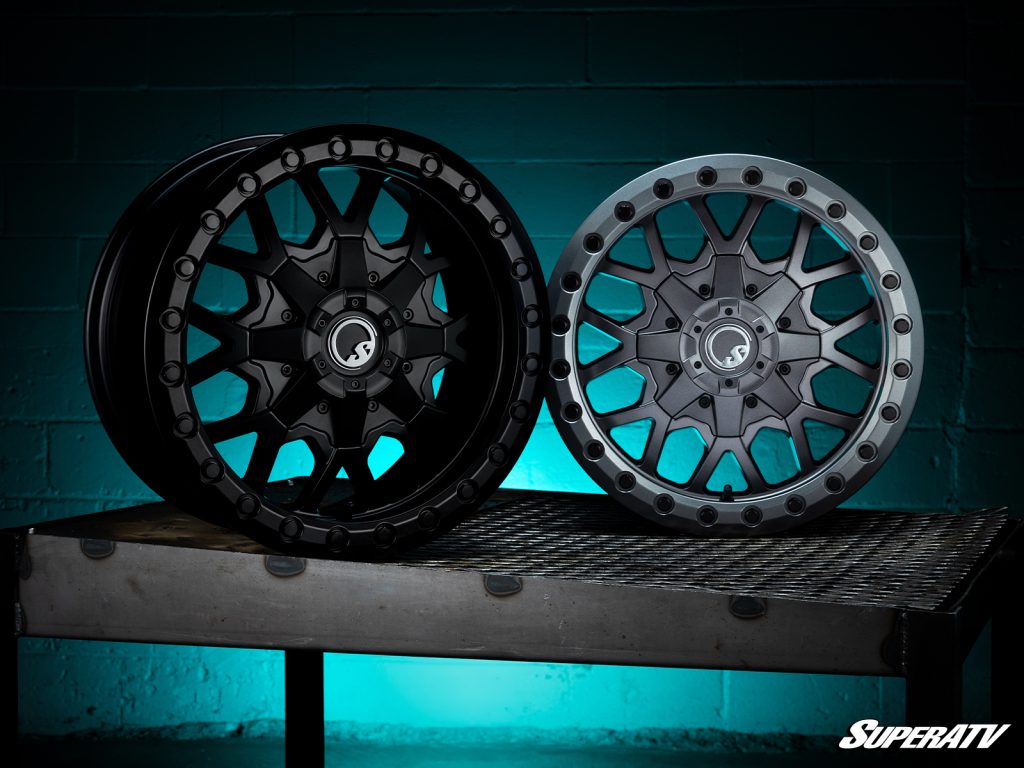 Two beadlock wheels without tires posed in front of a cyan light.