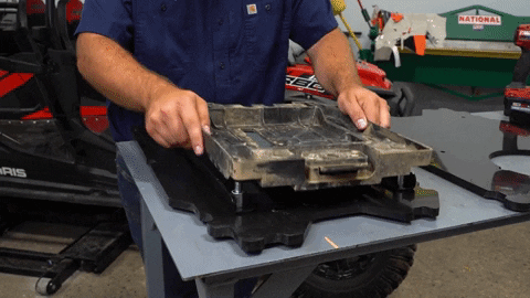 The man places the bottom of the OEM seat with the handle facing out towards the cutout.