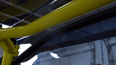 Two hands fit a bolt through a pre-drilled hole between the rear windshield and the roof.
