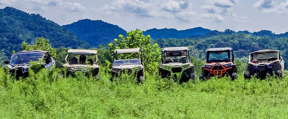 UTV lineup in field with mountains