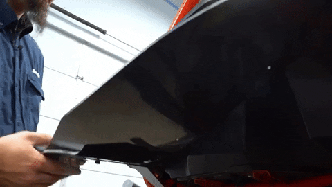 The bracket is being aligned to the underbody of the UTV for installation.