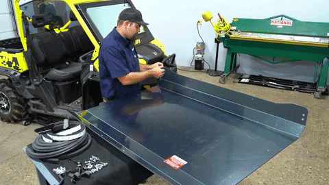 A technician (his name is Braden, actually) peels a light green protective film off a tinted polycarbonate roof.