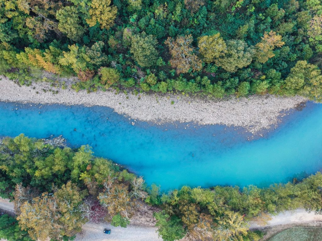 Aerial view of blue river going through woods