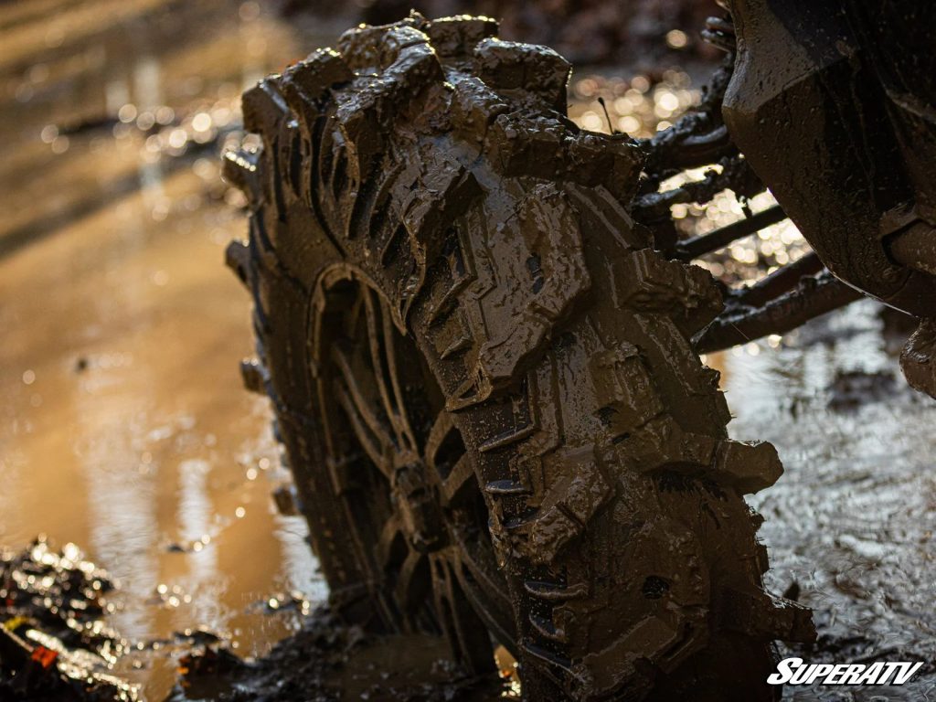 A giant tire with huge lugs buried in the mud.