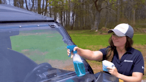 A short clip of a woman spraying down a UTV windshield with soapy water.