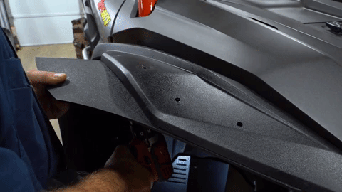 Now they're drilling through the hole in the flare into the OEM fender so the holes align.